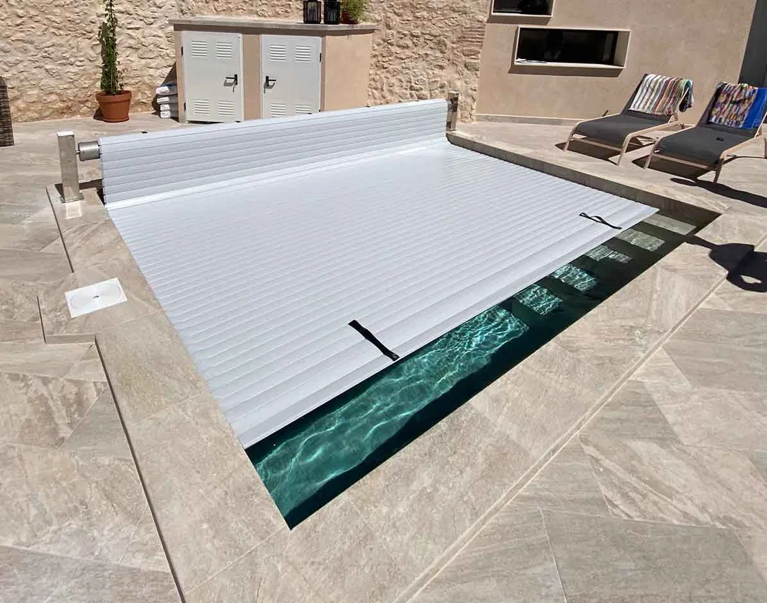 Cubierta automatica de lamas blancas semienrollada en una piscina moderna