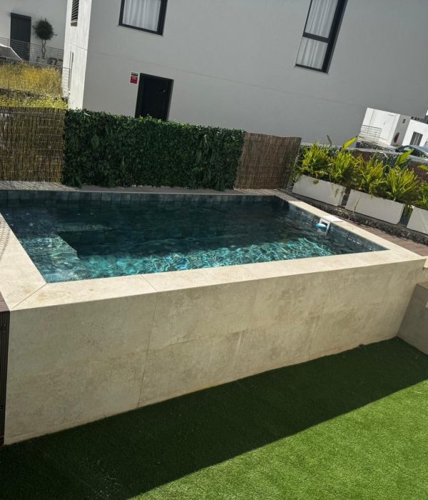 Piscina elevada terminada con escaleras laterales y zona ajardinada